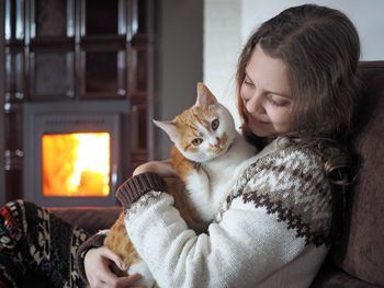 Close-up of girl with cat sitting at home