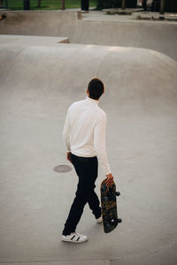 High angle view of man with skateboard walking at park