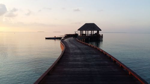 Pier over sea against sky during sunset