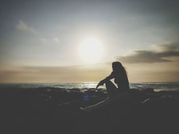 Silhouette man at beach against sky during sunset