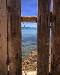 Wooden posts in sea against sky