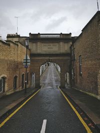 Road leading towards bridge against sky in city