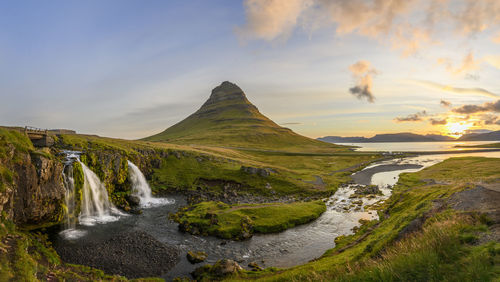 Scenic view of waterfall against sky during sunset