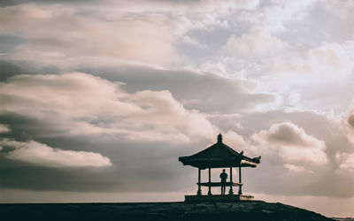 Lighthouse amidst sea and buildings against sky