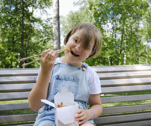 Teenage girl on a walk on a summer day in the park has lunch with noodles wok