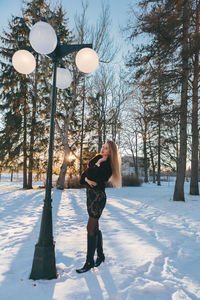 Full length of woman standing on snow covered tree