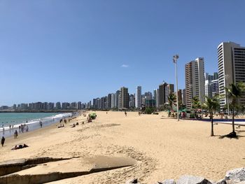 Panoramic view of beach and buildings against clear blue sky