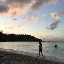 Rear view of man at beach against sky during sunset