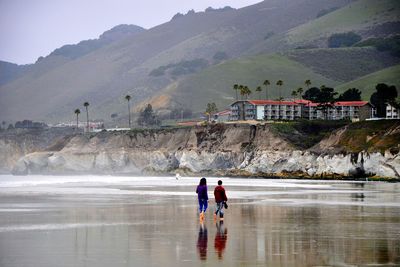 Rear view of men on beach against mountain range