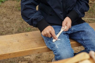 Midsection of man rubbing sand paper on wooden spoon