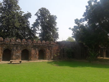 Built structure by trees on field against sky
