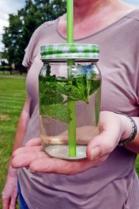 Midsection of woman holding fresh lemonade jar in park