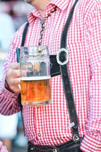 Midsection of man holding beer in jar