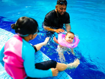 Father swimming with children in pool