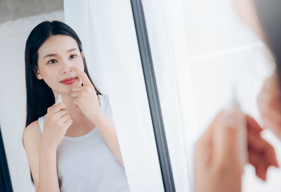 Portrait of young woman with reflection in mirror