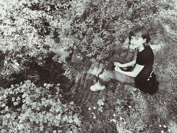 Side view of girl sitting on plant