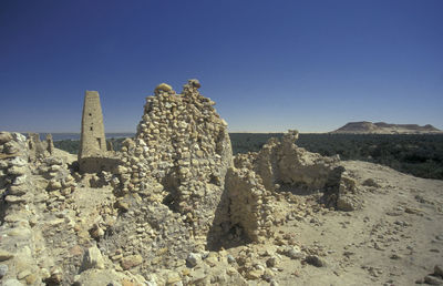 Rock formations on landscape against clear blue sky