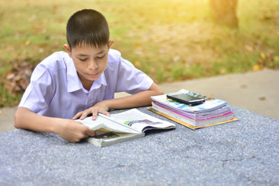 Boy reading book while sitting at marble