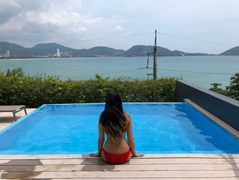 Rear view of woman looking at swimming pool against sea