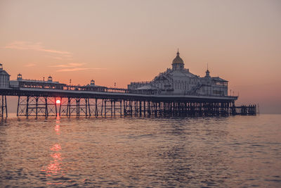 Eastbourne seafront at sunrise with calm sea and clear skies.