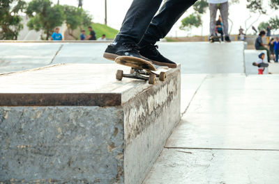 Low section of people skateboarding on footpath