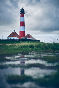 Lighthouse by sea against sky