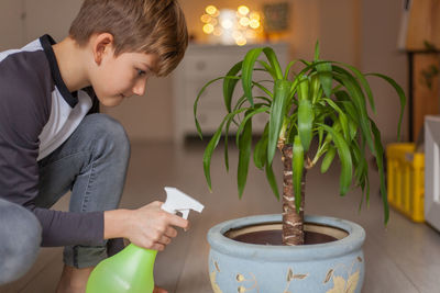 Side view of teenage boy holding potted plant