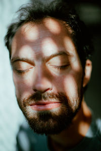 Close-up of eyes closed mid adult man with shadow on face