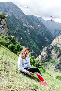 Woman sitting on grassy mountain