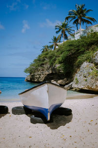 Lounge chairs and palm trees on beach against blue sky