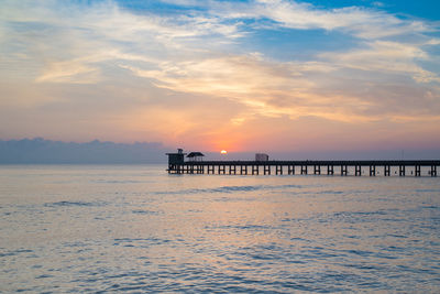 Pier over sea against sky during sunset