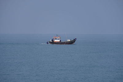 Boat sailing in sea against clear sky