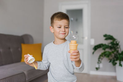 Child boy holding a soap bubble in his hands. children's games at home