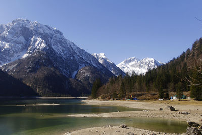 Scenic view of lake by snowcapped mountains against sky