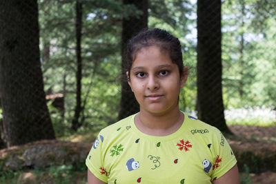 Portrait of young girl standing in forest