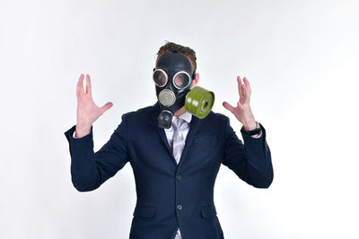 Well-dressed businessman wearing gas mask against white background