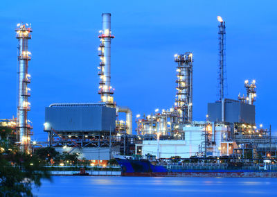 Illuminated factory against sky at night