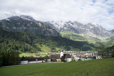 Houses on field by mountains against sky