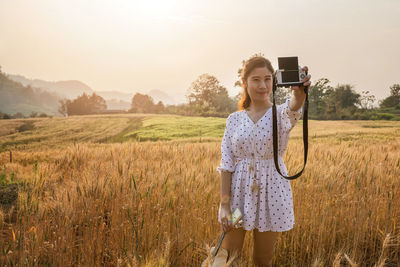 Rear view of woman photographing while standing on field