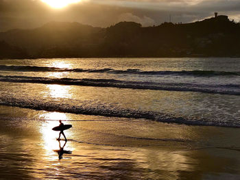 Silhouette person on beach against sky during sunset