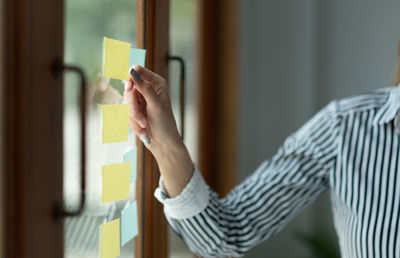 Hands of businesswoman sticking adhesive note on glass