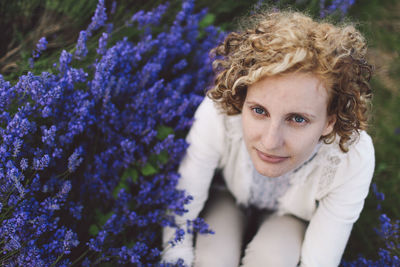 High angle view of woman sitting by lavender flowers on field