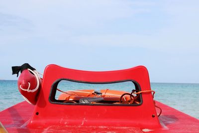 Red lifeboat at sea against sky