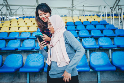 Full length of smiling woman standing against blue mobile phone