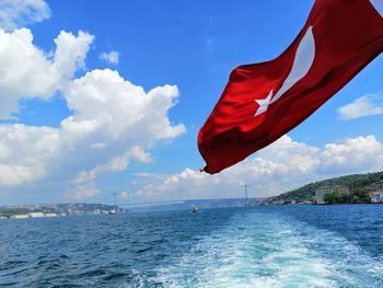 Red flag on sea against sky