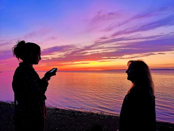 Side view of woman standing on beach during sunset