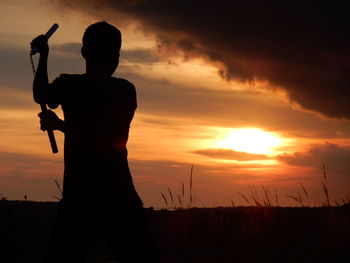 Silhouette man standing against orange sky