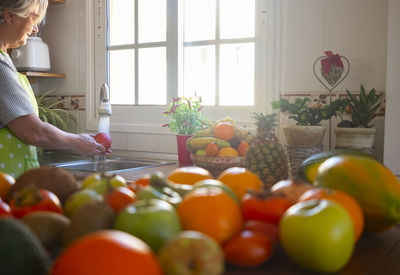 Side view of woman cleaning fruits in kitchen sink