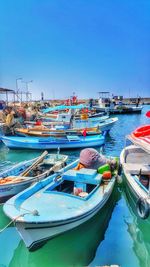 Boats moored in river at harbor against clear blue sky on sunny day