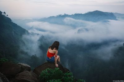 People sitting on rocks against mountains